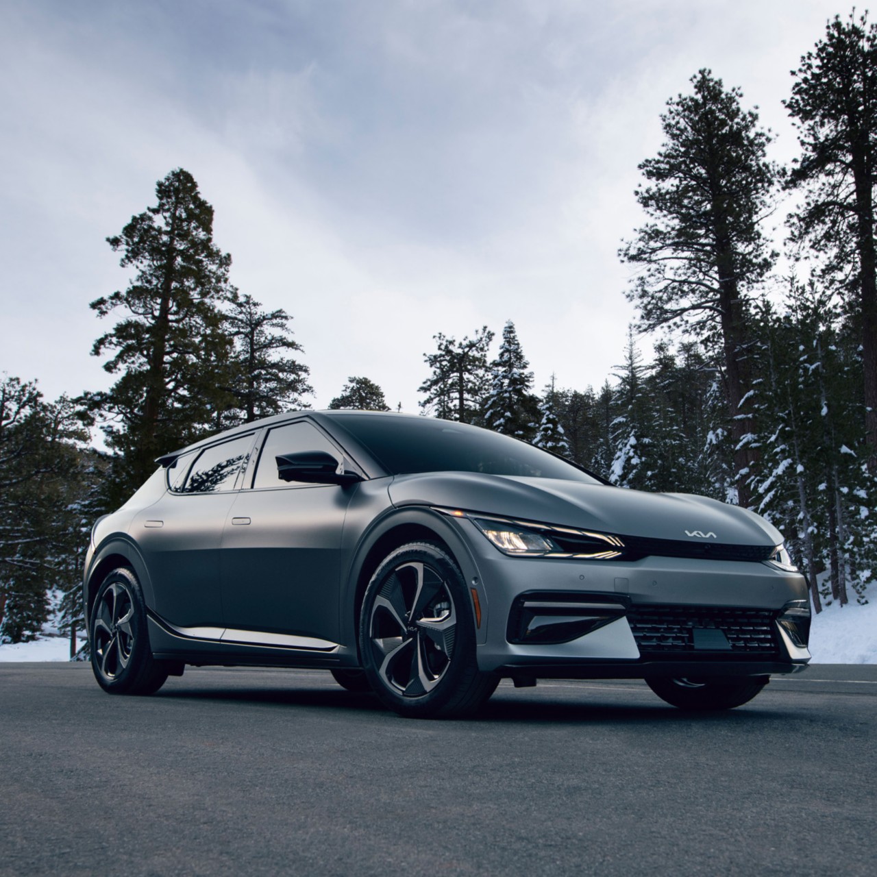 2024 Kia EV6 Utilizing Its Heat Pump Technology When Parked On A Forest Road With Snow Covered Trees Three-Quarter View