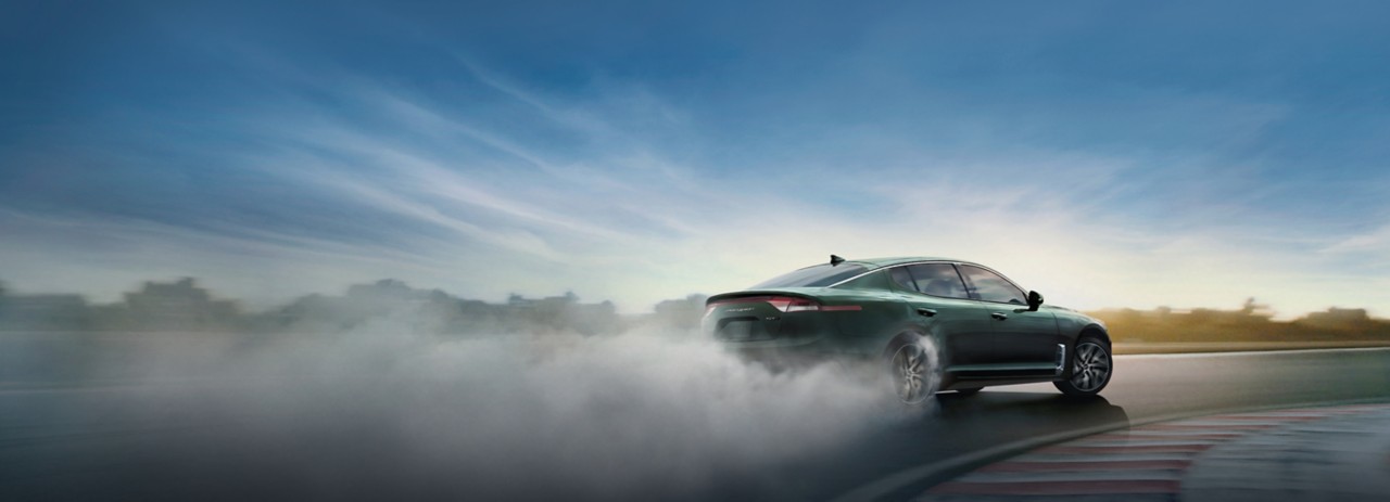 2023 Kia Stinger Driving Fast And Making A Sharp Turn On an Empty Racetrack Rear Three-Quarter View