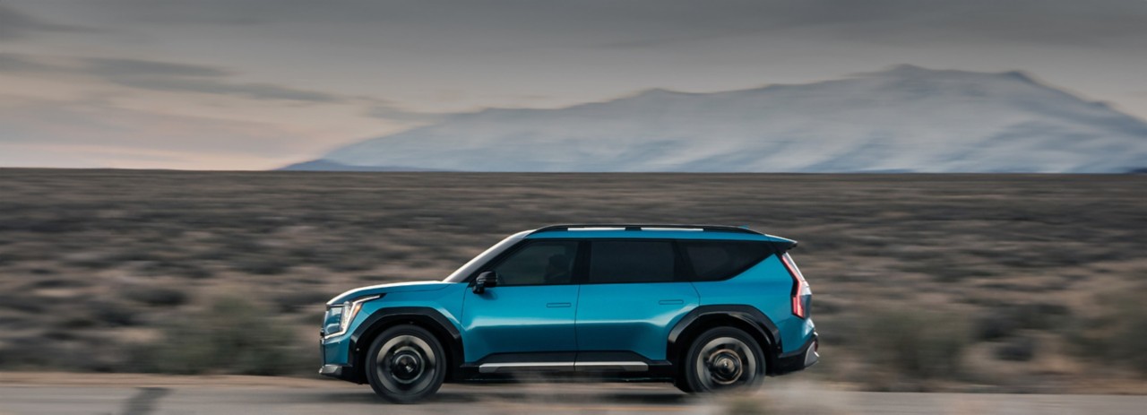Left Profile Blue EV9 driving on desert road