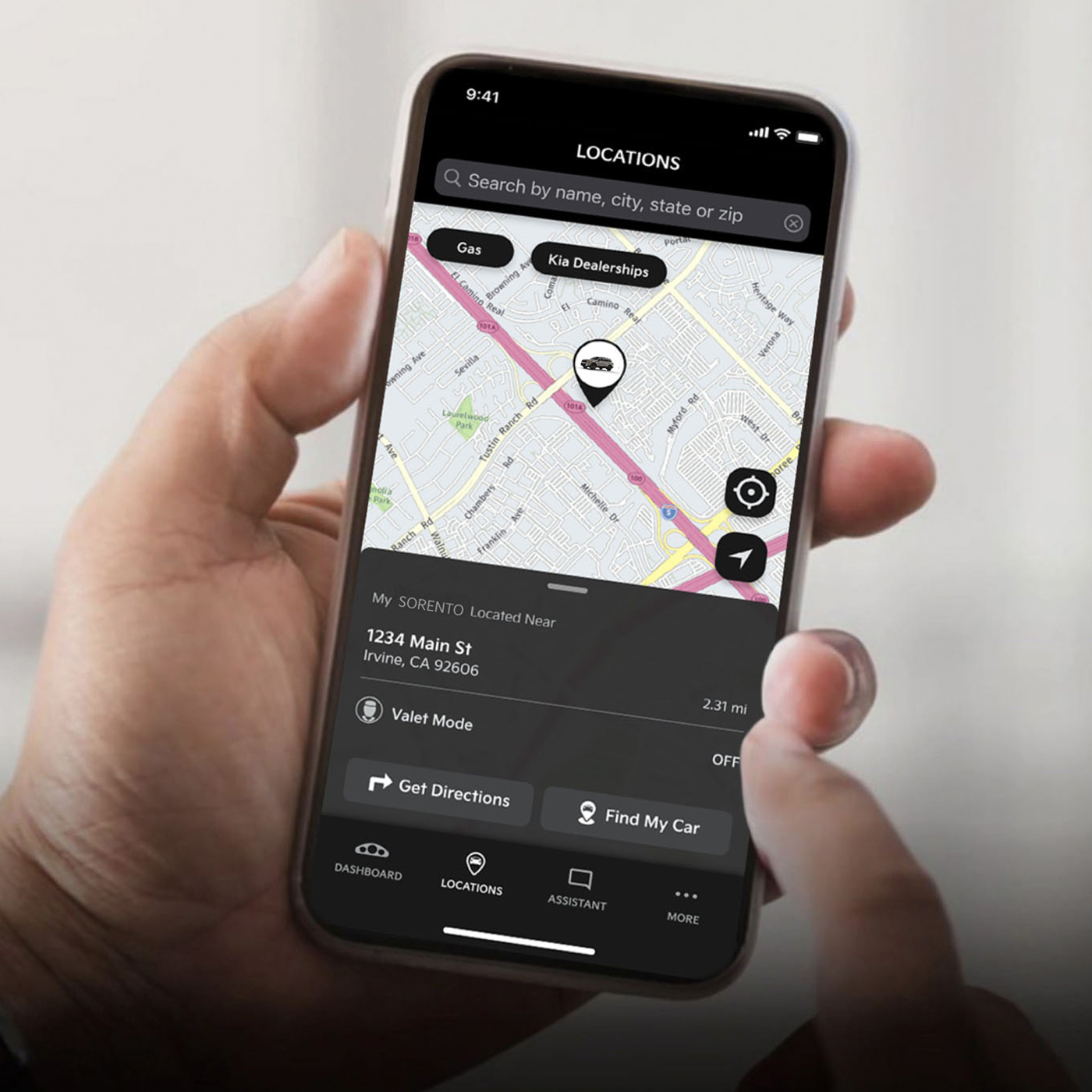A hand holding a phone, pointing to the screen that displays a map with a pin drop of the location of their car